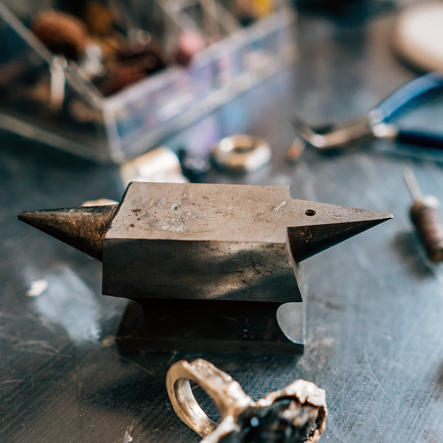 Jeweler's anvil on worktop surrounding by tools and works in progress