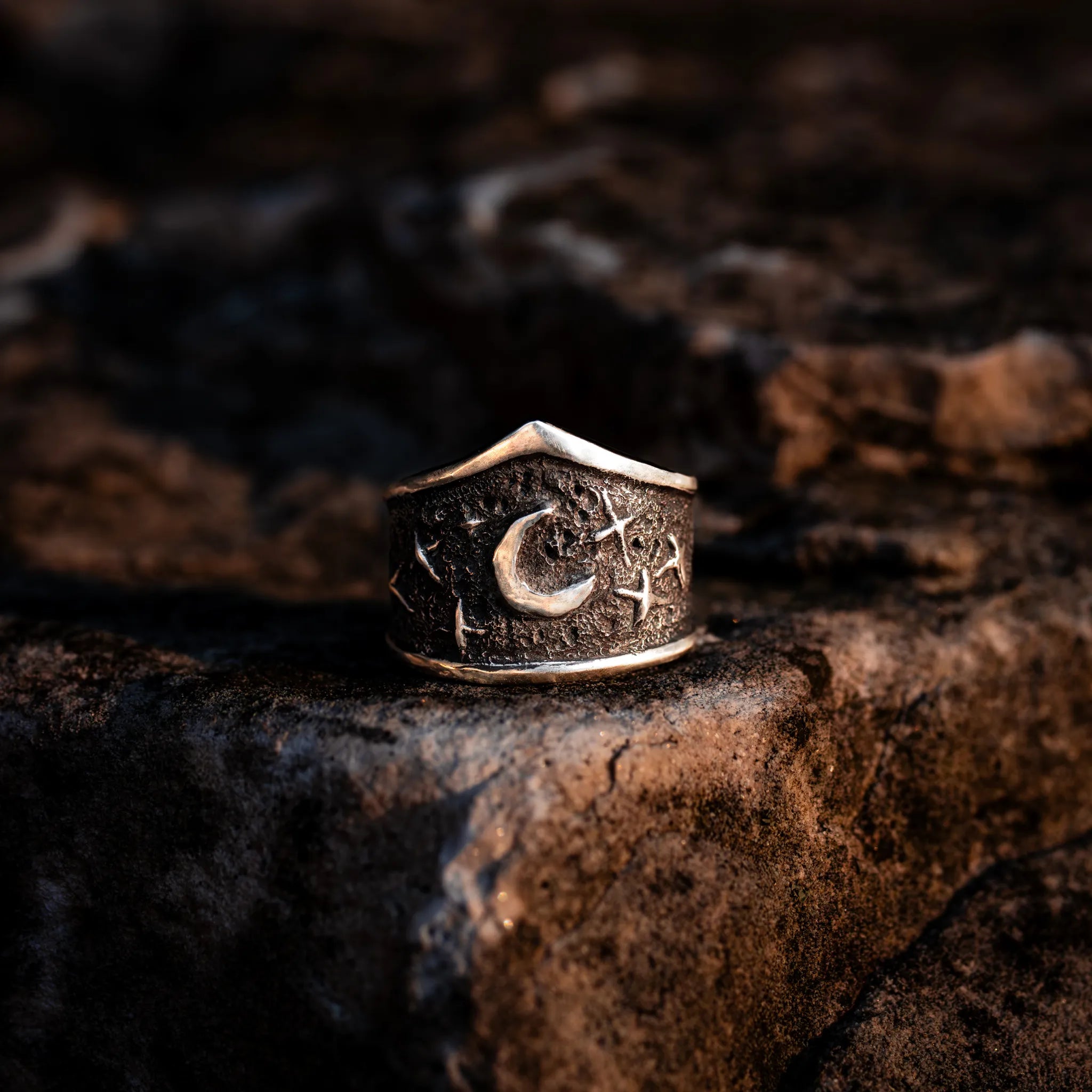 celestial ring with a crescent moon in the center and stars surrounding it. This ring is a wide,statement ring made from sterling silver and has an arched shape