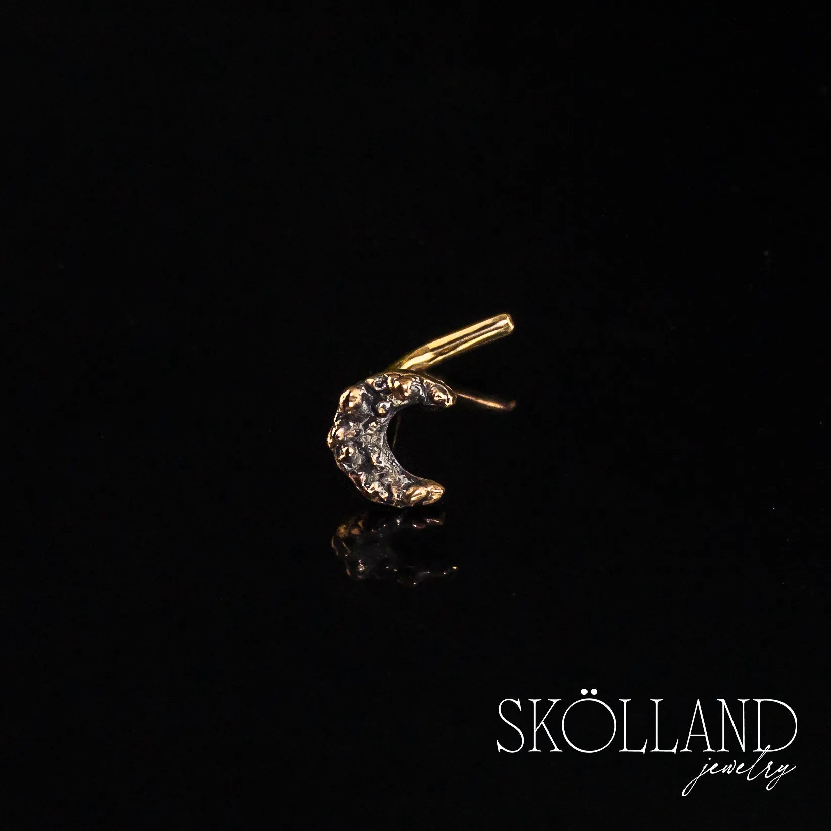 A real 14K yellow gold crescent moon nose stud on a black background, featuring a sparkling design.
