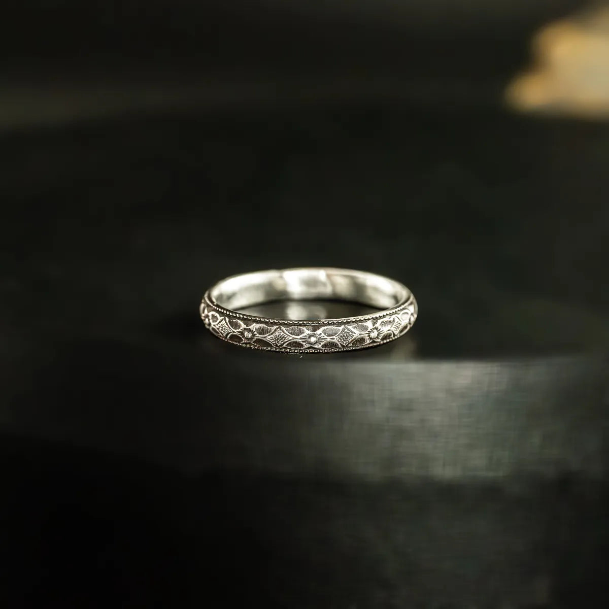 Close up of the fainty stacking ring. the ring is made from sterling silver and features little art deco/gothic flowers that run continuously around the band.