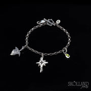 A sterling silver charm bracelet with a chain link design, featuring a charm that resembles a north star and another that appears to be a small ivy leaf with intricate detailing,and a green gemstone- tourmaline.