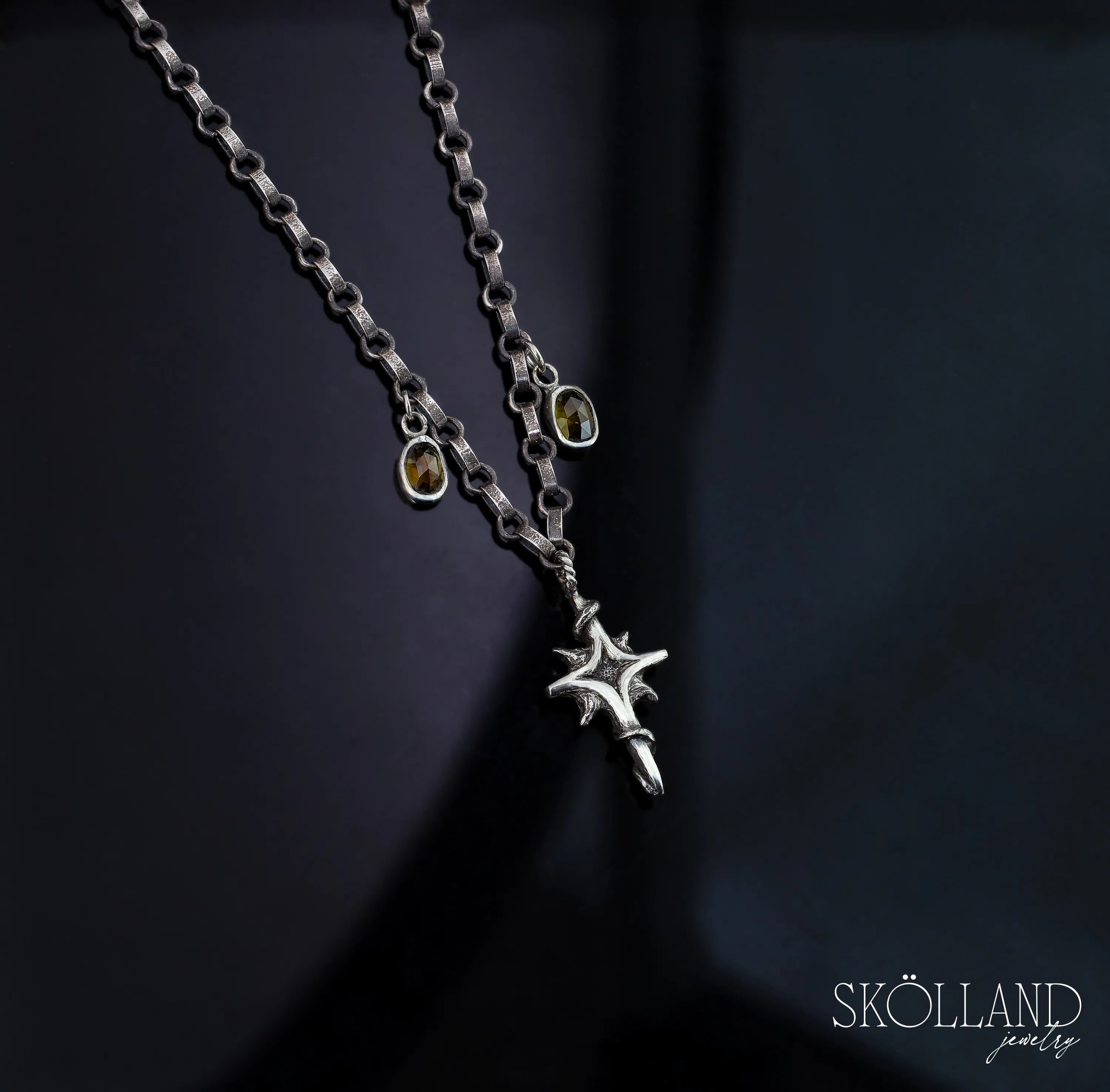 A sterling silver necklace with a star-shaped charm and two small gemstone charms on an 18-inch chain with a 2-inch extender, displayed against a dark background.