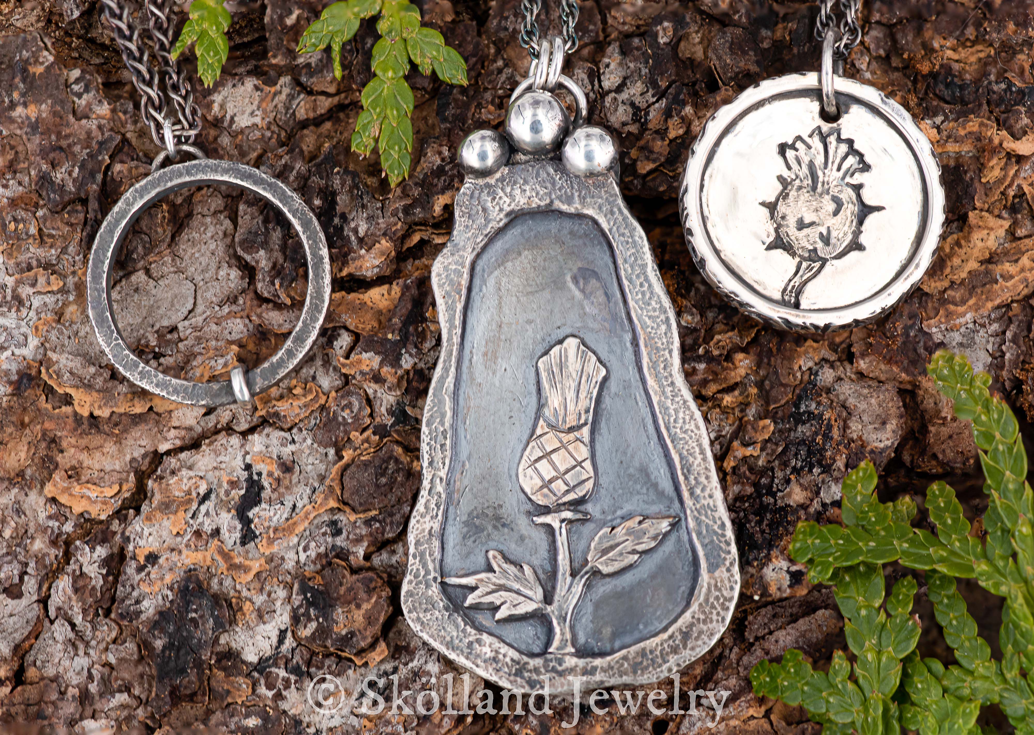 sterling silver thistle jewelry against a wood background