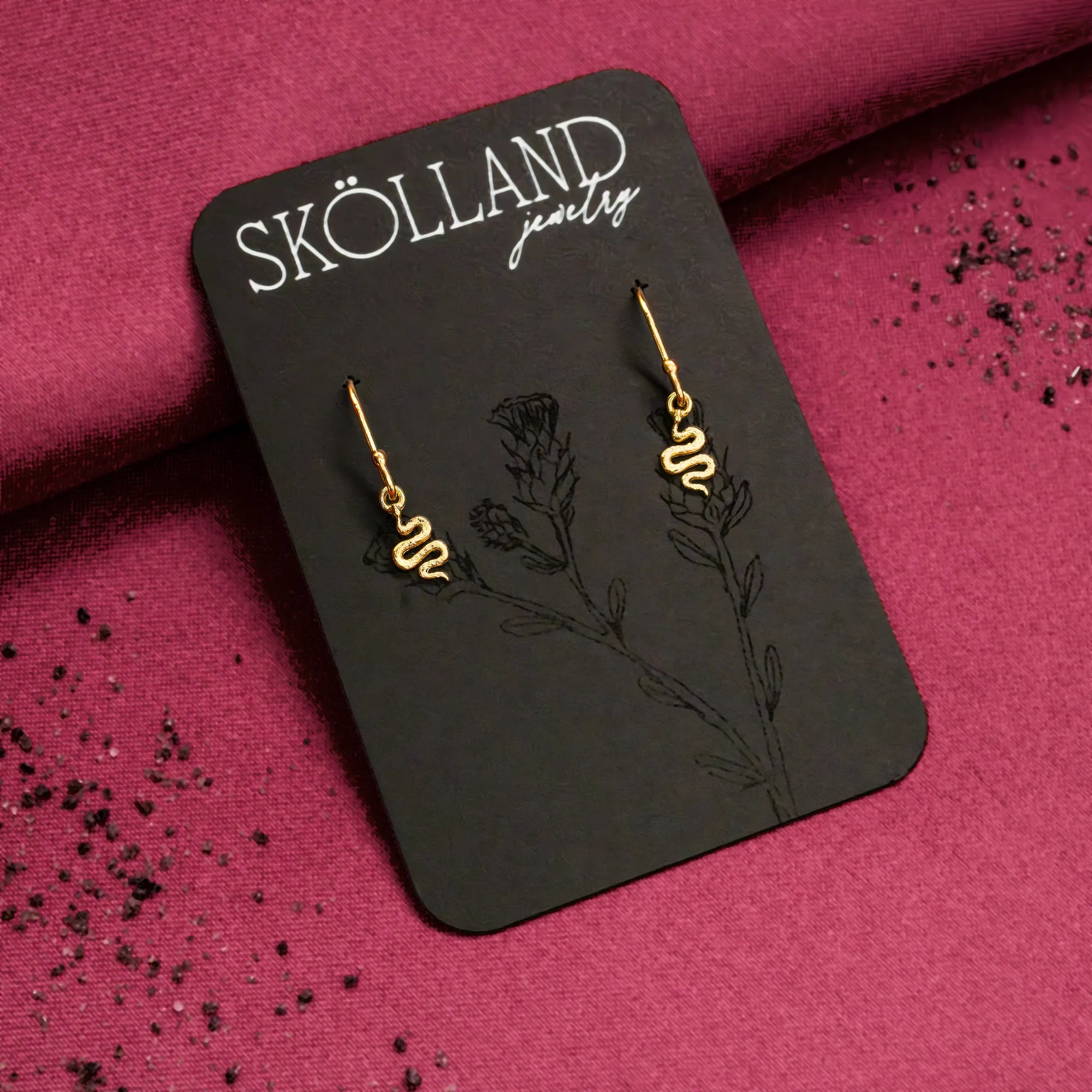 a pair of 14K yellow gold snake earrings on a black earring card. The snake charms are on ear wires, they easily move.