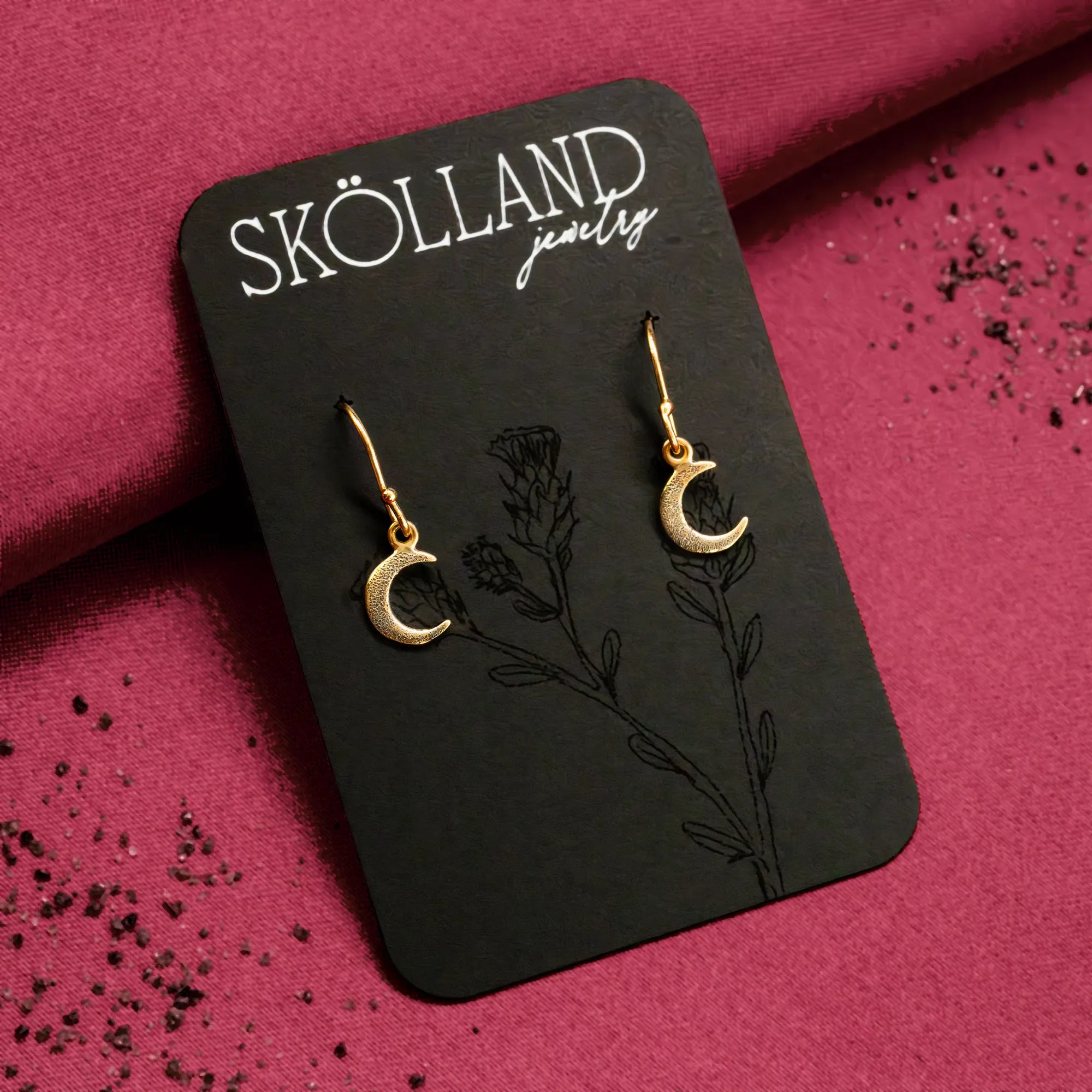 a pair of 14K yellow gold crescent moon earrings displayed on a black Skolland Jewelry earring card
