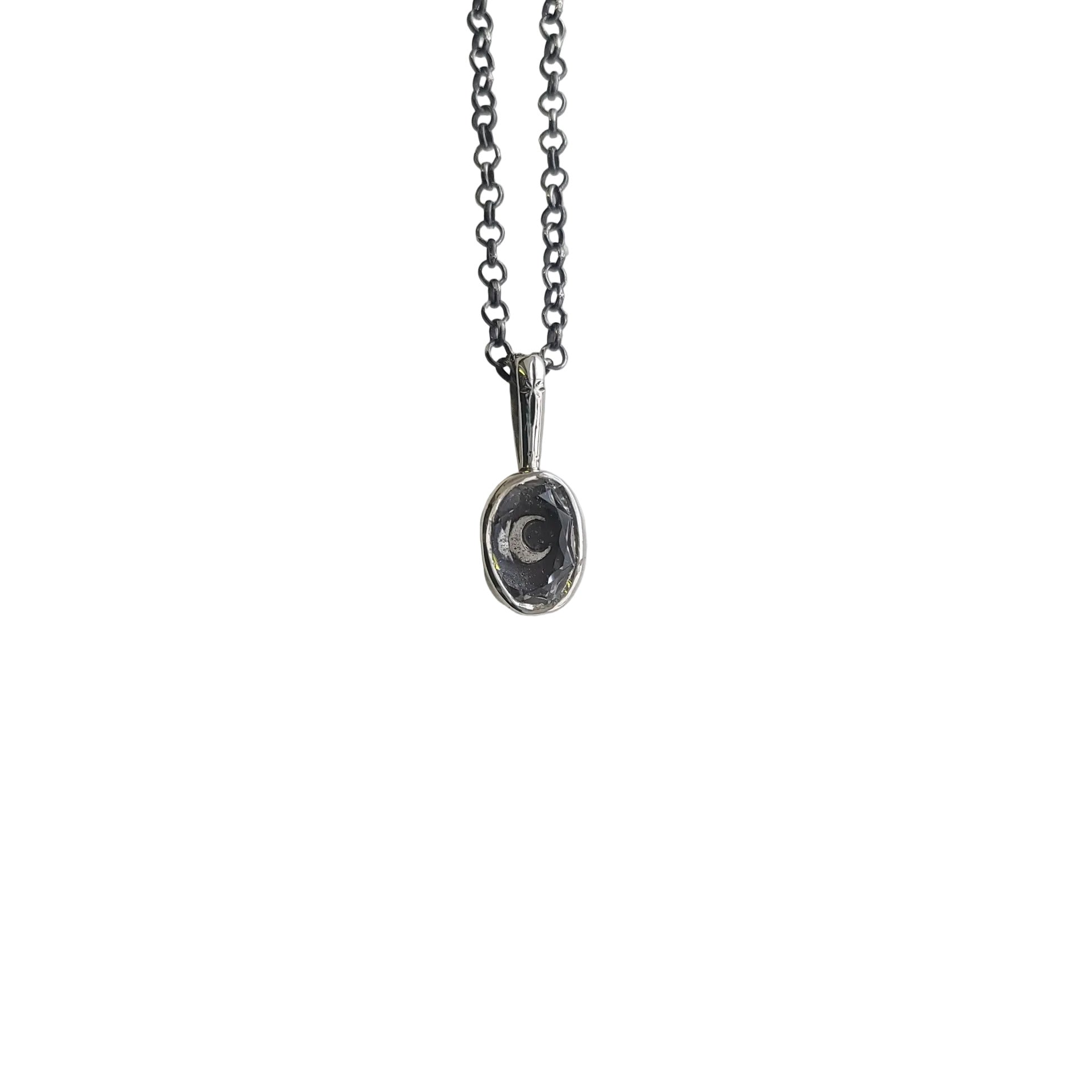 Silver necklace with a small bezel pendant that features a moon with a faceted clear quartz set on top