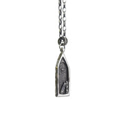 An artisan made silver necklace featuring a gothic style window, a north star, and books. The artist has named this piece "A light in the abbey"