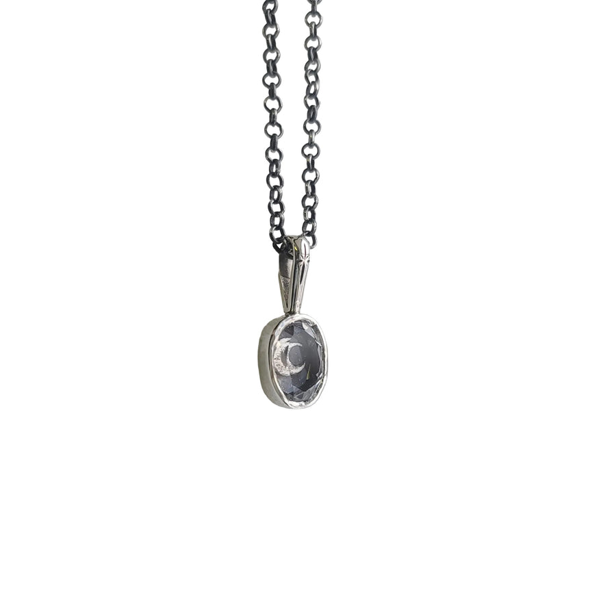 artisan made necklace that features a silver pendant with a bezel set clear quartz. The pendant features a hand engraved star detail in the front, and beneath the clear quartz is a crescent moon.