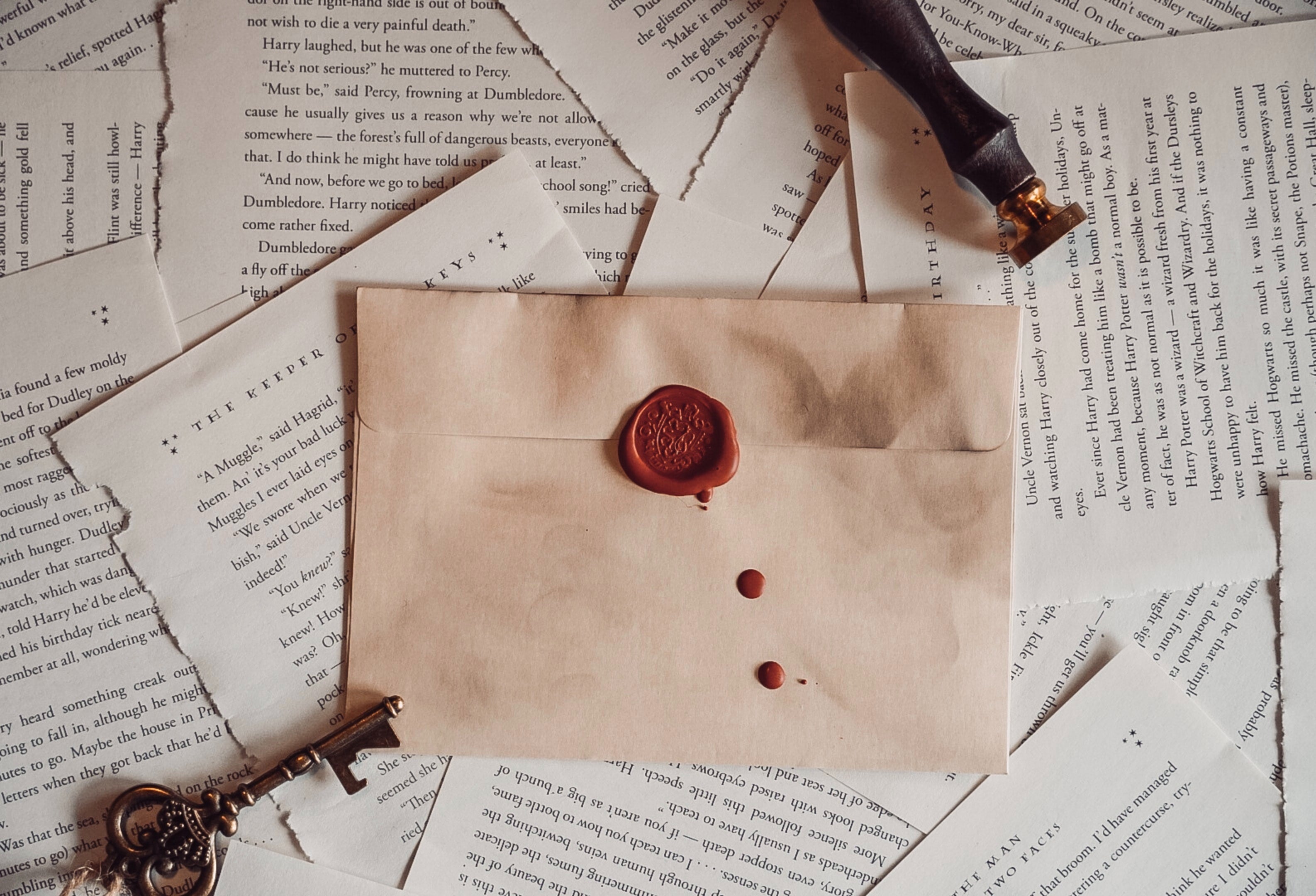 old letter with red wax seal, surrounded by harry potter pages,a brass key and wax stamp