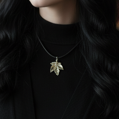 Person wearing a silver leaf pendant necklace against a dark background