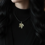 Person wearing a silver leaf pendant necklace against a dark background