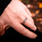 sterling silver filigree ring worn on a womans middle finger. The filigree pattern features a swirl and leaf pattern