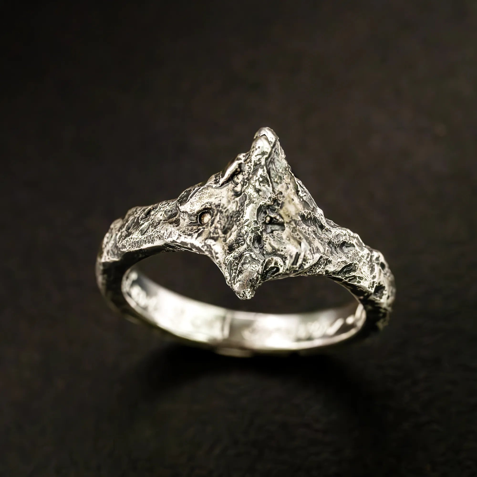 A brutalist, textured ring inspired by dark souls. The top is pointed like a v on both ends and features a darkened finish. Made entirely from argentium sterling silver.