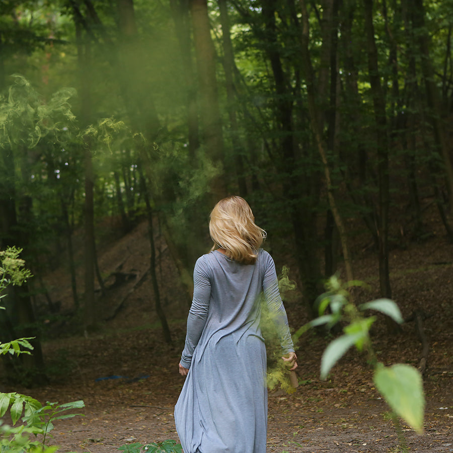 Blonde woman photographed from behind walking alone into a forest