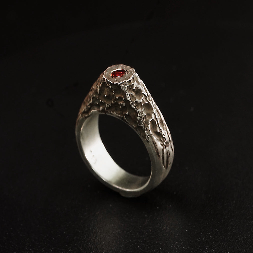 A domed, ireland insired mountain ring with a flush set garnet. Handmade from Argentium sterling Silver