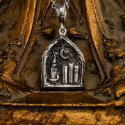 A sterling silver bookshelf necklace. In the center of the necklace lies 3 books, a candle and crescent moon. The scene is contained in an organic cathedral inspired frame.