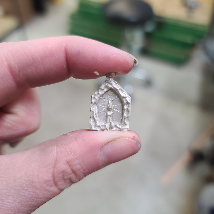Hand holding the small silver candle pendant before it was finished in its natural silver state. 