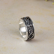 Silver ring with intricate thistle and knot work designs on a beige background