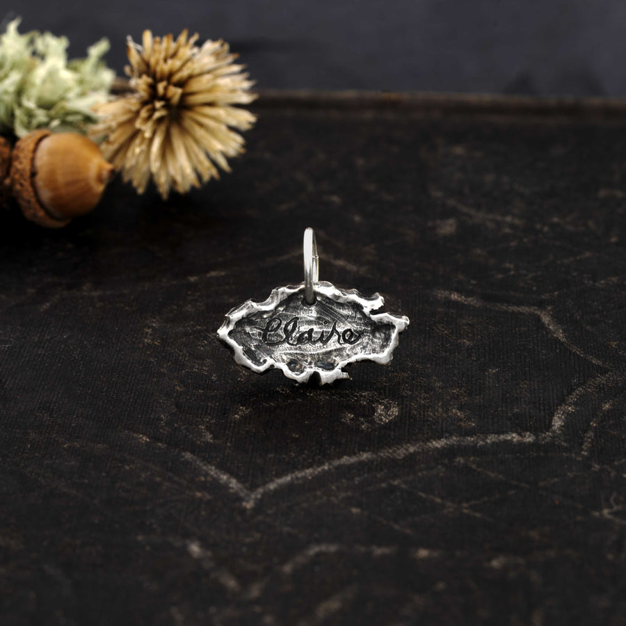 a head on photos of the lost messages charm that reads the name "Claire" in cursive. The charm has uneven edges that resemble a torn piece of paper. The charm is antiqued for dimension & character.