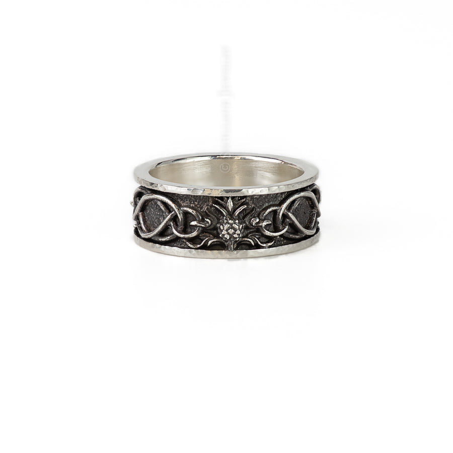 a head on shot of the thistle and highland interlace ring. the ring features hammered details at the top, and a thistle linking the knot work details
